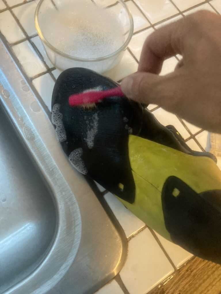 scrubbing outside sole to clean climbing shoe